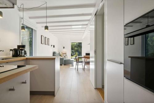 a kitchen with white cabinets and a living room at Cozy Holiday Home Near The Isefjord in Kirke-Hyllinge