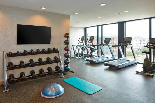 a gym with a bunch of exercise equipment and a flat screen tv at AC Hotel by Marriott Des Moines East Village in Des Moines