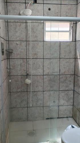 a bathroom with a glass shower with a toilet at Casa Espaçosa a 200m da praia in Florianópolis