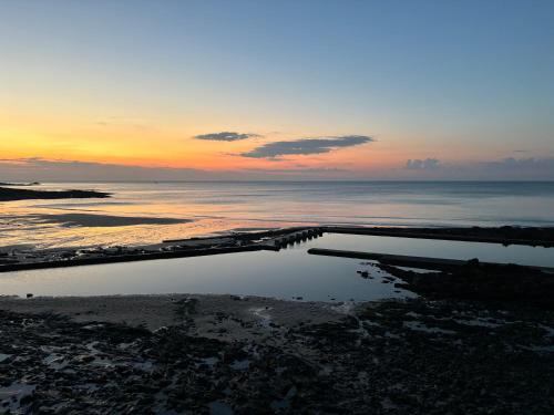 un coucher de soleil sur l'océan avec une masse d'eau dans l'établissement Appartement, à Granville