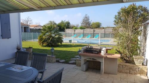 Un patio con mesa y sillas y una piscina. en maison île de Ré avec piscine chauffée et vélos, en Le Bois-Plage-en-Ré