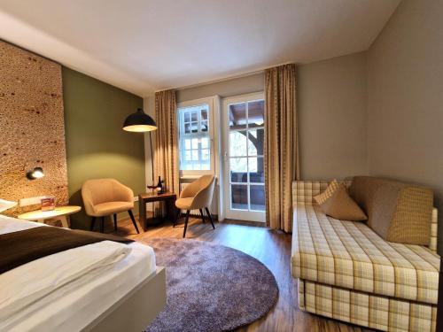 a bedroom with a bed and a couch and a table at Hotel-Gasthaus Goldener Engel in Glottertal