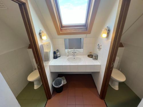 a bathroom with two toilets and a sink and a window at La Ferme Saint Pierre de Glabais in Genappe