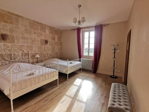 une chambre avec deux lits et un mur en pierre dans l'établissement Superbe Château et son Gîte de Château de l'Estang à Saint Emilion, à Saint-Genès-de-Castillon