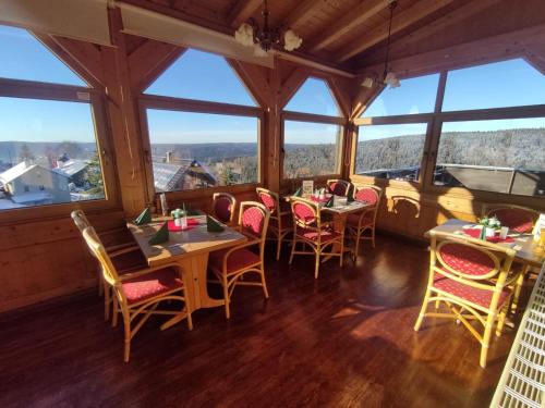 a restaurant with tables and chairs and large windows at Berggasthaus & Pension Schöne Aussicht in Klingenthal