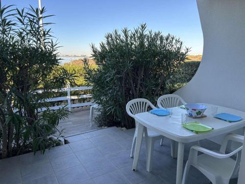 une table blanche et des chaises sur une terrasse dans l'établissement Port Camargue, T2 climatisé, terrasse, parking, animaux admis - FR-1-250-219, au Grau-du-Roi
