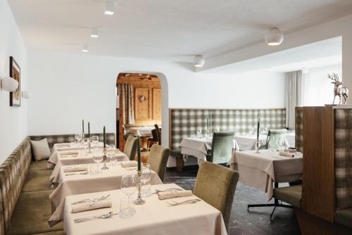a row of tables in a restaurant with white tablecloths at Hotel Pradat in Corvara in Badia