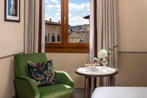 a green chair and a table in a room with a window at Tivoli Palazzo Gaddi Firenze Hotel in Florence