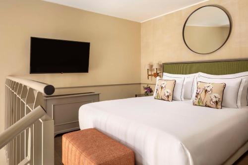 a hotel room with a large bed and a mirror at Tivoli Palazzo Gaddi Firenze Hotel in Florence