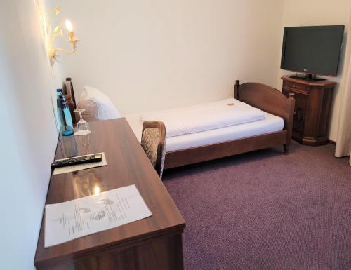 a small room with a bed and a desk and a tv at Hotel Rössle in Fürstenberg