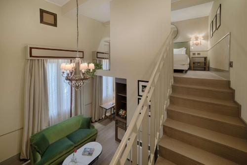 a living room with a staircase and a green couch at Tivoli Palazzo Gaddi Firenze Hotel in Florence
