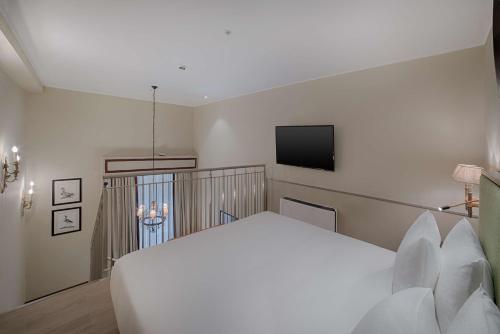 a bedroom with a white bed and a flat screen tv at Tivoli Palazzo Gaddi Firenze Hotel in Florence
