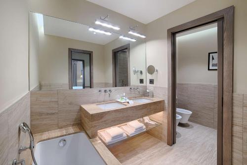 a bathroom with a tub and a sink and a toilet at Tivoli Palazzo Gaddi Firenze Hotel in Florence