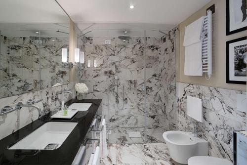 a bathroom with two sinks and a marble wall at Tivoli Palazzo Gaddi Firenze Hotel in Florence