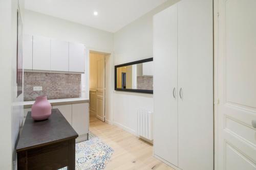 Chambre blanche avec un vase sur une table dans l'établissement Au cœur des Batignolles -Bail mobilité - 1 chambre, à Paris
