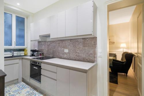 une cuisine avec des placards blancs et une salle à manger dans l'établissement Au cœur des Batignolles -Bail mobilité - 1 chambre, à Paris