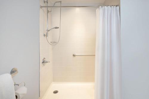 a shower with a white shower curtain in a bathroom at Courtyard by Marriott New York JFK Airport in Queens