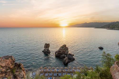 an island in the middle of the water at sunset at Hotel Kalura in Cefalù