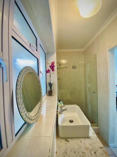 a bathroom with a sink and a mirror at Watching Waves, Heron Chase in Fish Hoek