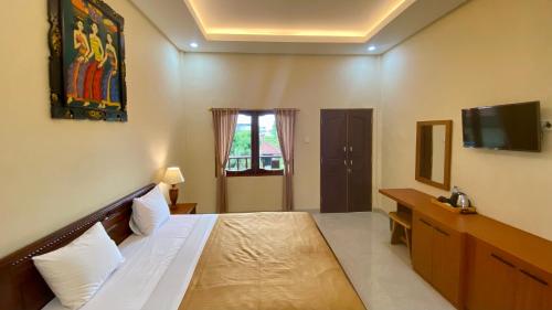 a bedroom with a bed and a desk and a television at Bali Sandy Resort in Kuta