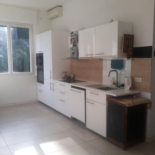 une cuisine avec des placards blancs et une grande fenêtre dans l'établissement Villa Nicole avec Spa professionnel, à Carry-le-Rouet