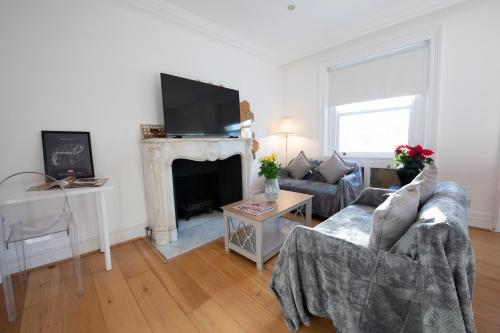 a living room with a couch and a fireplace at Harrods Flats in London