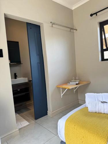 a bedroom with a blue door and a yellow bed at Purple Steps Guest House in Kimberley