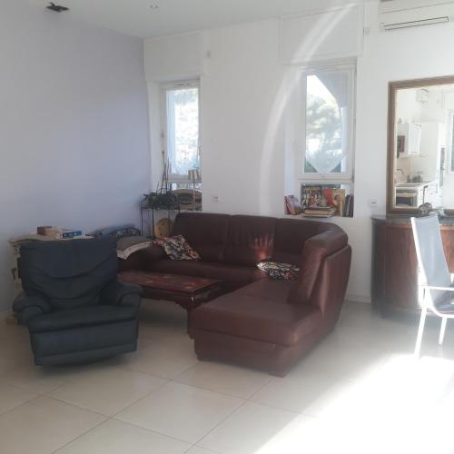 - un salon avec un canapé brun et une chaise dans l'établissement Villa Nicole avec Spa professionnel, à Carry-le-Rouet