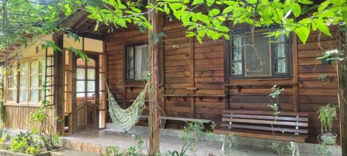 a log cabin with a hammock on the porch at Sítio com Casa de Madeira com 2 quartos 100m2 px Centro de Salesópolis in Salesópolis