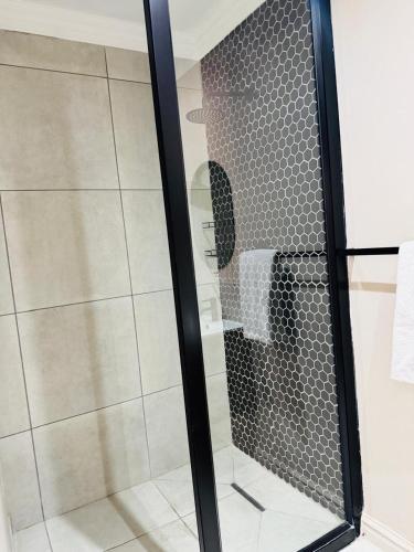 a shower with a glass door in a bathroom at Purple Steps Guest House in Kimberley