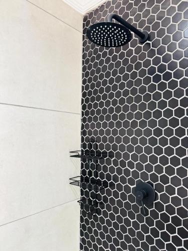 a shower with a black and white tiled wall at Purple Steps Guest House in Kimberley