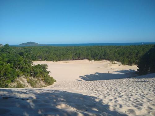 a view of a sandy beach with trees in the distance at Suite casal em casa compartilhada com uma pessoa - estacionamento - Trilha Moçambique in Florianópolis