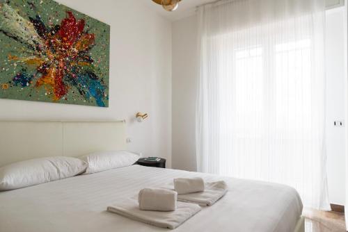 a bedroom with a white bed with a painting on the wall at Youhosty - Paul Valery Bis in Milan