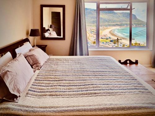 a large bed in a bedroom with a large window at Watching Waves, Heron Chase in Fish Hoek