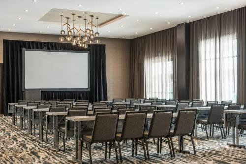 a conference room with tables and chairs and a projection screen at AC Hotel by Marriott Worcester in Worcester