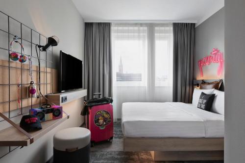 a hotel room with a bed and a tv at Moxy Duesseldorf City in Düsseldorf