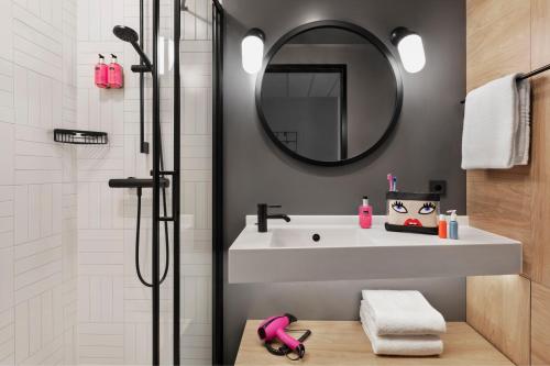 a bathroom with a white sink and a mirror at Moxy Duesseldorf City in Düsseldorf