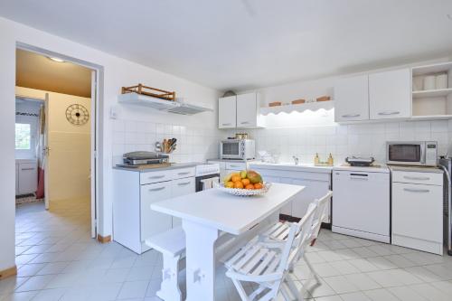 a kitchen with white cabinets and a bowl of fruit on a table at Pierre Idyllique - Climatisée avec grand jardin in Saumont