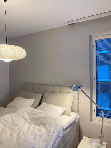 a bedroom with a bed and a lamp and a window at Saunallinen Lutakon kaksio järvinäkymin in Jyväskylä