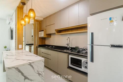 a kitchen with a white refrigerator and a counter at Condomínio a beira-mar c/ piscina - SHC in Piçarras