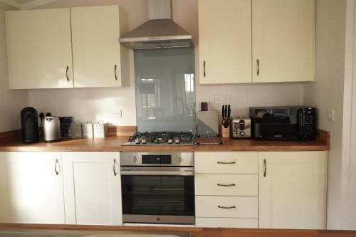 a kitchen with white cabinets and a stove top oven at Hollicarrs - Bumblebee Lodge in York