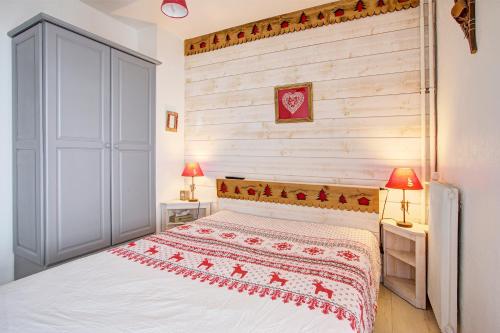 a bedroom with a white bed and a wooden wall at Soleil et Montagne - Au pied station les Angles in Les Angles