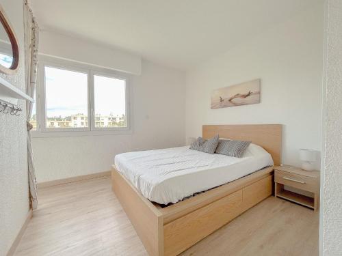 une chambre blanche avec un lit et une fenêtre dans l'établissement Appt lumineux avec terrasse cœur de ville 35 m², à Saint-Raphaël