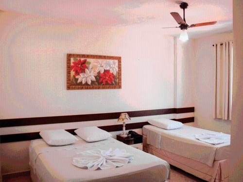 a bedroom with two beds and a painting on the wall at Hotel Pais e Filhos in São João del Rei