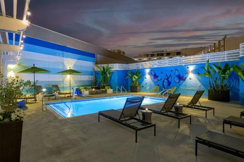 a pool with chairs and tables and a blue wall at Renaissance Los Angeles Airport Hotel in Los Angeles