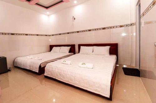 two beds in a room with white sheets and towels at Khách sạn Thảo Lợi in Con Dao