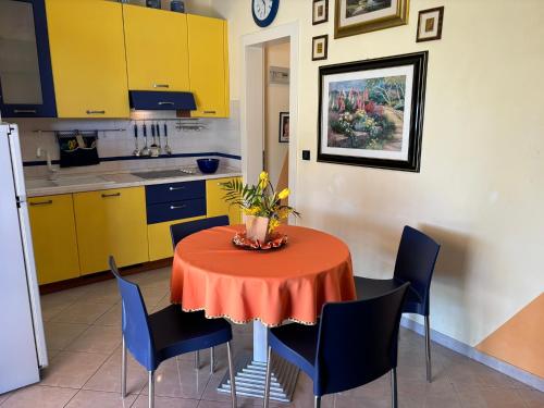 a kitchen with a table with chairs and yellow cabinets at Villa Atlante in Bibione