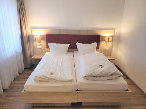 two beds with white sheets and pillows in a room at Hotel Rössle in Fürstenberg