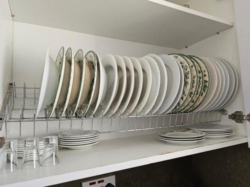 ein Regal mit weißen Platten und Schalen in der Unterkunft Two bedroom holidays apartment, walking distance to the beach and Harbour in Paphos