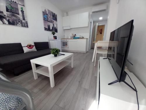 a living room with a couch and a tv and a table at Apartamento n3, a 10 min del aeropuerto in San Fernando de Henares